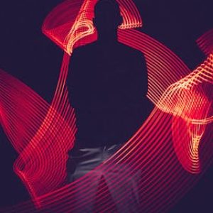 pexels-photo-3094799-3094799 A silhouette of a person surrounded by artistic red light trails, creating a dynamic visual effect.